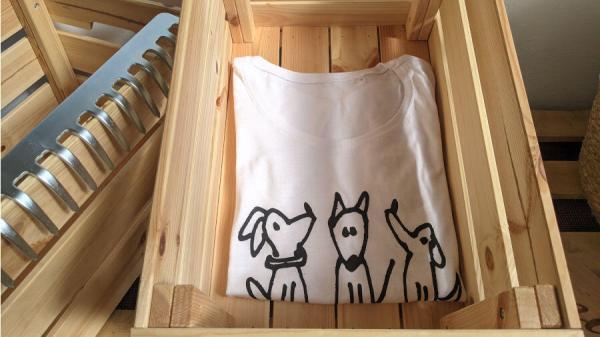 t-shirt trio cagnolini realizzata in cotone con stampa sublimatica disegno di marco ferrari per Toscani store piegata in cassetta legno